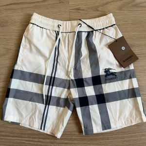 Rutiga Burberry badshorts - Snygga Burberry shorts i klassiskt beige och svart rutigt mönster. Perfekta för sommaren och riktigt clean look. Materialet känns lätt och luftigt, perfekt för varma dagar. Pris går att doskuteras och bara hör av er om ni har någon fråga!😁