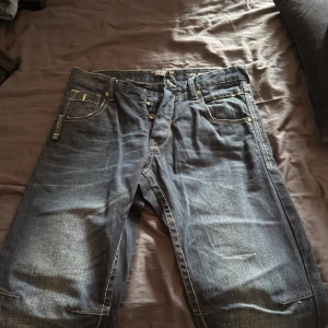 Jack & Jones mörkblå jeans - Mörkblå jeans från Jack & Jones Core Workwear med snygga slitningar och kontrastsömmar. Klassisk femficksmodell och läderpatch bak i midjan. Jeansen har rak passform och är tillverkade i slitstarkt denimtyg.