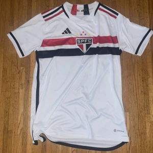 Vit Sao Paolo fotbollströja - Snygg vit fotbollströja från Adidas med SPFC-logga på bröstet. Köpt i Brasilien och helt oanvänd. Storlek M men sitter som XS. Pris kan diskuteras.