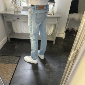 Levi's 511 ljusblå jeans, vintage  - Säljer ett par Levi's 511 jeans i ljusblå tvätt. Modellen är slim och har klassiska fem fickor, knappgylf och en liten slitning på ena knät för en cool look. Jeansen är raka i benen och har den ikoniska läderpatchen bak i midjan.