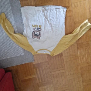 Gul och vit långärmad tröja N'Seen - Långärmad tröja från N'Seen i storlek XXL. Tröjan är vit med gula ärmar och har ett gulligt tryck med texten 'IN LOVE' och en tecknad björn på bröstet. Perfekt för dig som gillar lekfulla och färgglada plagg.