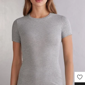 Ljusgrå basic t-shirt i bomull - Enkel och stilren ljusgrå t-shirt med rund hals och korta ärmar. Modellen är figurnära och passar perfekt till jeans eller kjol. Tillverkad i mjuk bomull för maximal komfort och en clean look.