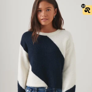 Svartvit stickad tröja med diagonal design - Snygg stickad tröja i svart och vitt med en fet diagonal färgblock-design över hela framsidan. Tröjan har rund halsringning och långa ärmar. Perfekt för dig som gillar en stilren men ändå unik look.