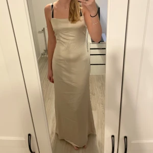Champagnefärgad långklänning storlek S - Säljer en elegant champagnefärgad långklänning med smala axelband och snygg snörning i ryggen. Klänningen har en rak, tight passform och är tillverkad i ett glansigt satinliknande material. Perfekt för bal eller festliga tillfällen! Storlek S. Klänningen har funnits på Nelly för 800 kr och säljer nu för 300 kr 💖
