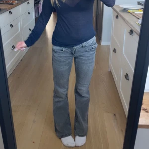 Grå bootcut jeans med låg midja - Säljer ett par grå jeans med bootcut-modell och låg midja. Jeansen har klassiska fickor fram och bak samt snygga sömdetaljer. Perfekta för dig som gillar en avslappnad men trendig look.