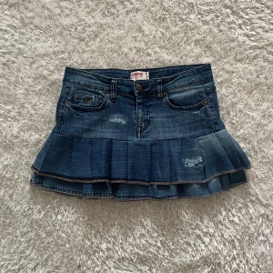 Jeanskjol med volang  - Lågmidjad jeanskjol omsydd från ett par jeans. Midjemått tvärsöver- 37cm Längd- 32cm