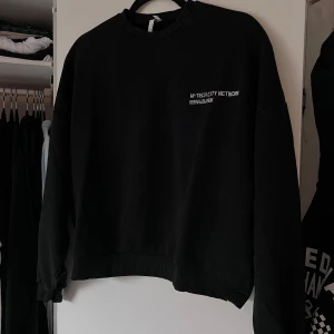 Svart sweatshirt med tryck - Säljer en svart sweatshirt med tryck på bröstet. Tröjan har långa ärmar och ribbade muddar vid ärmslut och nederkant. Oversized. Perfekt för en avslappnad stil. 🖤 Önskar du veta exakta mått? Tveka inte att höra av dig!