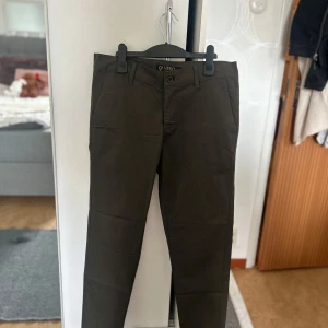 Mörkgröna chinos från Vero Fly - Snygga mörkgröna chinos från Vero Fly i storlek 32. Klassisk rak passform med knäppning och bälteshällor. Perfekta för en stilren look och passar till många olika tillfällen.