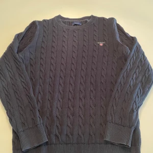 Mörkblå kabelstickad tröja från GANT - Säljer en mörkblå/svart stickad Gant tröja. Denna säljer jag för 400 kr. Jag säljer en liknande Gant tröja i samma färg och storlek, om man köper båda så kan får ni dem för 700kr. MEN priset är inte hugget i sten och går absolut att förhandla om!