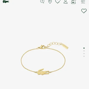 Guldarmband med krokodilberlock från Lacoste - Elegant guldarmband från Lacoste med en ikonisk krokodilberlock. Armbandet har en tunn kedja och justerbar längd för perfekt passform. Perfekt för att lägga till en touch av stil till din outfit. Jag har använt den 1 gång eftersom att den inte passar mig ,