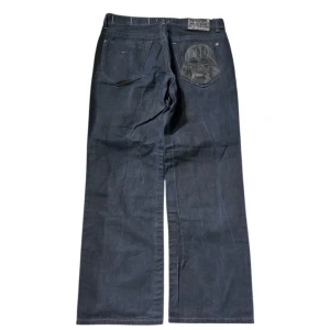 Ecko jeans med star wars  - Unika svarta jeans från Marc Ecko med coola Star Wars-detaljer. Byxorna har en broderad Darth Vader på bakfickan och en liten Darth Vader-knapp. Perfekta för Star Wars-fans som vill sticka ut!