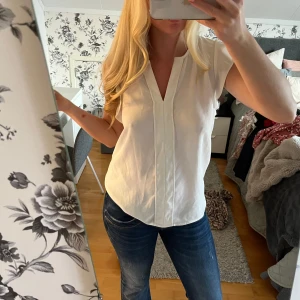 Vit blus med v-ringning - Säljer en stilren vit blus med v-ringning och korta ärmar. 