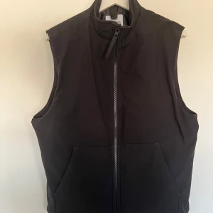 Svart väst från Jack & Jones - Säljer en svart väst från Jack & Jones i storlek M. Västen har hög krage, dragkedja framtill och två stora fickor.