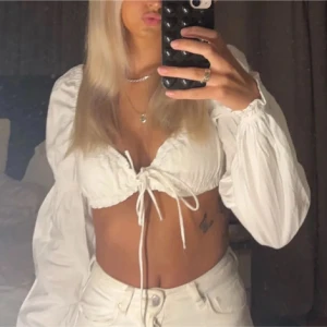 Vit blus med knytning - Säljer en snygg vit blus med långa ärmar och knytning framtill. Perfekt för en trendig look.