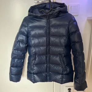 Mörkblå dunjacka med huva från United Colors of Benetton - Marinblå jacka, inte mycket använd! Nypris-900kr