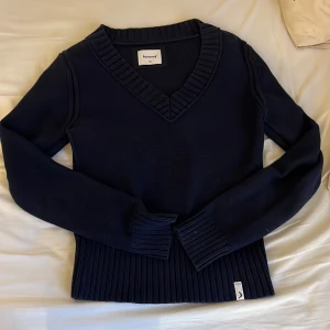 Mörkblå stickad tröja med v-ringning från Boomerang - Säljer en mörkblå stickad tröja från Boomerang i 100% bomull. Tröjan har v-ringad hals, bred ribbad mudd i nederkant och ärmar samt klassisk passform. Perfekt för lager-på-lager och stilren look. Bara att höra av sig vid frågor😊