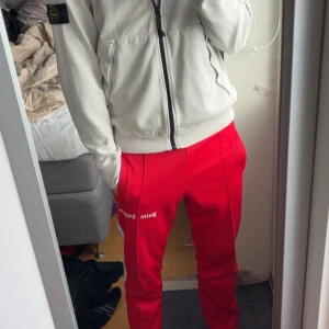 Röda byxor från Palm Angels 100% äkta - Snygga röda byxor från Palm Angels med vit text på benet. Byxorna har en elastisk midja och vita ränder längs sidorna. Väldigt bra skick , 100% äkta byxor , Storlek S , passar väldigt bra för dom som är mellan 175-185. Palm angels är rätt så stora i storlekar så storlek S är perfekt för 175-185