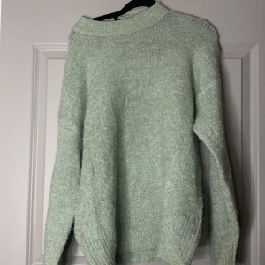 Ljusgrön stickad tröja - Mysig ljusgrön stickad tröja med rund halsringning och långa ärmar. Tröjan har en enkel och klassisk design med ribbade muddar vid ärmslut och nederkant. Perfekt för en mysig kväll, och enkel att styla!