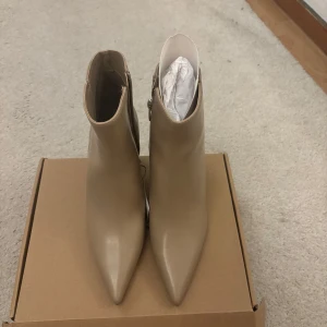 Beige boots med klack från MANGO - Säljer ett par stilrena beige boots från Mango med klack och spetsig tå. Supersnygga men tyvärr för små för mig. Lapp och lådan de kom i är kvar, så de är helt oanvända! Köpt för 599kr och säljer för 350kr!