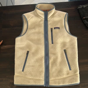 Beige fleeceväst från Patagonia - Säljer en beige fleeceväst från Patagonia med ljusblå detaljer och dragkedjor. I storlek S