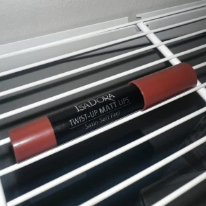 Isadora Twist-Up Matt Lips läppenna - Matt läppenna från Isadora i en lite mörkare röd/rosa nyans. Pennan har en twist-up funktion och ger en satinmatt finish med mjuk känsla på läpparna. Har försökt ta bild i 2 olika ljus så att man kan se färgen lite bättre. Har använt den som rouge, men det går att skrapa av toppen ganska enkelt om man skulle vilja det.