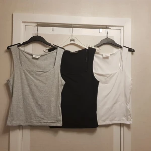Nya Ärmlösa Toppar med fyrkanyig halsringning - Set om 3 strl S - Säljer tre enkla och stilrena linnen i färgerna grå, svart och vit från ginatricot.  Alla har breda axelband och rak passform, perfekta att matcha till olika outfits. Materialet känns mjukt och stretchigt bomull och elastian 
