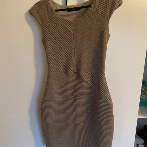 Beige tight klänning från Collection LOB - Säljer en beige tight klänning från Collection LOB med korta ärmar och snyggt ribbat mönster. Klänningen har en figurnära passform och markerad midja.