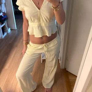 Ljusgula vida linnebyxor med snörning m topp - Säljer ett par ljusgula limmebyxor med tillhörande topp, helt nya har bara tagit av prislappen på tröjan och byxan e använd en gång, storlek Xs men passar även S