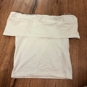 Off shoulder topp - En stilren vit tubtopp med bred kant upptill. Toppen är axelbandslös och har en enkel, clean look som passar perfekt till jeans eller kjol. Mjuk och stretchig för en bekväm passform.