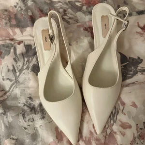 Vita pointy slingback pumps från Nelly - Snygga vita pumps från Nelly med spetsig tå och låg klack. Endast använd 1 gång i storlek 37, men har repor på spetsen men inte något som syns när man går🤍köpt för 449kr från Nelly men säljer för 250kr ( priset kan diskuteras) 