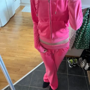 Rosa set med kofta och byxor - Säljer ett rosa set med zip-kofta och matchande byxor. Hoodien har dragkedja, snörning i huvan och fickor på sidan. Byxorna har resår och snörning i midjan samt raka ben. Köptes ifrån Busnel. Storlek 40 men sitter som S.