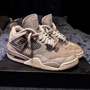 Nike Air Jordan 4 Retro frozen moments - Snygga Nike Air Jordan 4 Retro i Taupe Haze med beige och grå toner. Ovandel i mocka och skinn, coola metalliska detaljer och meshpaneler på sidorna. Klassisk Jumpman-logga på häl och plös. Perfekta sneakers för dig som gillar stilrena och unika detaljer. Anväder ej, kan tvättas till lite om behövs.