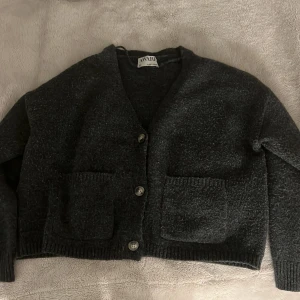 Mörkgrå stickad cardigan  - Mörkgrå cardigan med fickor på sidan, tröjan är från aware