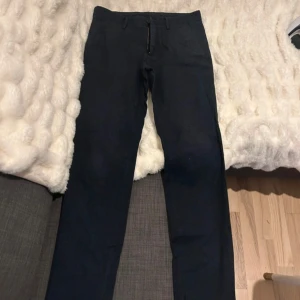 Mörkblå slim fit byxor Massimo Dutti - Snygga mörkblå slim fit byxor från Massimo Dutti. Klassisk design med dragkedja, knappstängning och bälteshällor. Byxorna har två fickor fram och två bakfickor med knapp. Perfekta för en clean och stilren look.