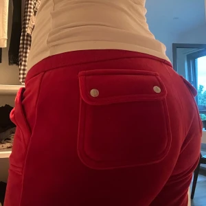 Röda mjukisbyxor med snörning - Snygga röda mjukisbyxor med raka ben och coola fickor bak med knappar. Byxorna har snörning i midjan och är gjorda i ett mjukt material som känns skönt mot huden. Perfekta för chill dagar eller när du vill vara bekväm men ändå se fräsch ut.