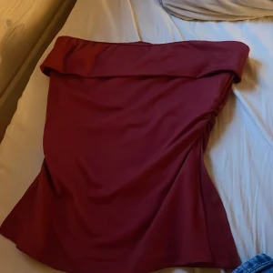 Vinröd tuptopp - Tub topp med bred volang upptill och draperad detalj i sidan. Aldrig använd