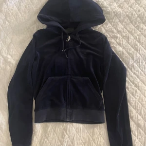 Mörkblå velour hoodie Juicy Couture XS - Mörkblå hoodie från Juicy Couture i mjuk velour med huva, snörning och dragkedja framtill. Tröjan är mycket använd och väl omhändertagen om. 