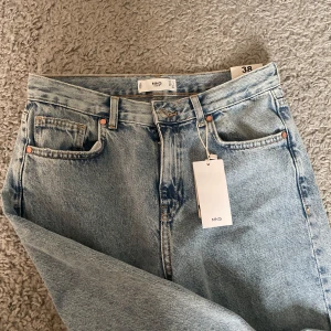 Ljusblå raka jeans från MNG, strl 38 - Ljusblå jeans från MNG i rak modell med klassisk femficksdesign och midwaist. Jeansen har en snygg tvättad look och är tillverkade i bomull. Perfekta för dig som gillar en clean och tidlös vibe.