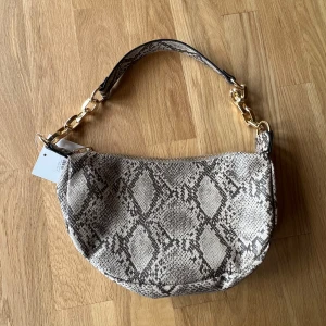 Oanvänd väska med mönster   - Helt oanvänd väska med lappen kvar! Köpt på Nelly för ett tag sedan💕väskan har guldig kedja på sidorna. 