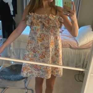 Blommig kortklänning från H&M - Supersöt blommig kortklänning från H&M i linnemix. Klänningen har volang upptill, smala axelband och en luftig passform. 