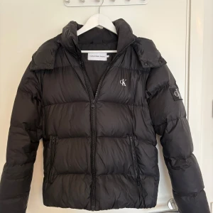 Svart pufferjacka från Calvin Klein Jeans - Riktigt fet Calvin Klein Jeans pufferjacka. Storlek S. Andvänd 1 vinter men inga större defekter. Nypris ca 1500kr. Pris kan diskuteras vid snabb affär! 