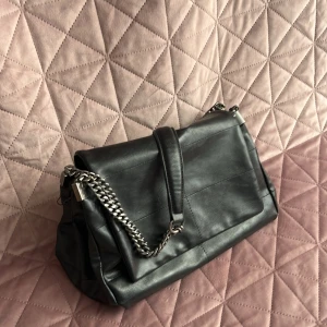 SÅLD - Svart kedje väska med axelrem. Den har tre stora fack och ett litet sidofack. Mycket bra skick och knappt använd.