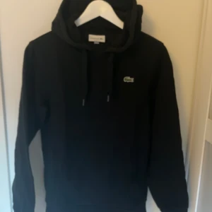 Lacoste hoodie  - Säljer en superbekväm hoodie som är perfekt för alla tillfällen! Den är tillverkad av mjukt material som håller dig varm och skön. Perfekt för både avslappnade dagar hemma och äventyr ute på stan. Missa inte chansen att lägga vantarna på denna mångsidiga och stilrena hoodie!om du vill köpa den kontakta mig gärna😁👍 