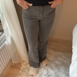 Grå bootcut jeans med hög midja - Säljer ett par grå jeans med bootcut-modell och hög midja. Byxorna har synliga sömmar framtill, klassiska bakfickor och är i ett mjukt denimtyg. Perfekta för dig som gillar en retroinspirerad look med lite utsvängda ben.