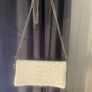Vit väska - jättesöt vit kuvertväska från even&odd köpt på zalando med nitstenar på. Tappat lite färg på kedjan men inget som syns tydligt annars inget fel💓 Säljs pga av att jag inte använder längre