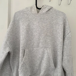 Ljusgrå oversized hoodie - Mysig ljusgrå hoodie med stor huva och magficka. Oversized passform och ribbade muddar vid ärmslut och nederkant. Insidan är mjuk och fleecefodrad, perfekt för kyliga dagar. Enkel och stilren design som funkar till allt.