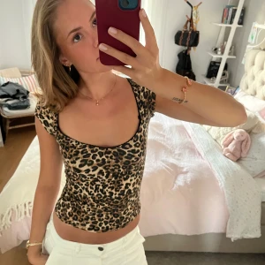 Leopardmönstrad croppad topp - Säljer en croppad topp med leopardmönster och korta ärmar. Toppen har en fyrkantig ringning och sitter tight mot kroppen. Färgerna går i beige, brunt och svart. Perfekt för dig som vill sticka ut med en trendig look.