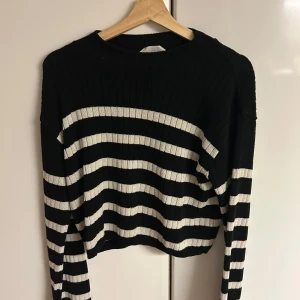 Svartvit randig stickad tröja - Randig svart och vit stickad tröja med ribbad struktur. Tröjan har lång ärm och en något loose passform, perfekt för dig som gillar en avslappnad stil. Klassisk rund halsringning och mjukt material som känns skönt mot huden. Inte fri frakt! 