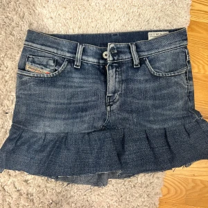 Jeanskjol med volang från Diesel - Snygg blå jeanskjol från Diesel med volangkant nertill och råa kanter. 