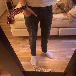 Slim Glenn svarta jeans med slitningar - Säljer ett par svarta Slim Glenn jeans från Jack & Jones. Jeansen har slim fit, skinny ben och snygga slitningar på framsidan för en trendig look. Tillverkade i stretchig bomullsdenim som sitter skönt hela dagen.